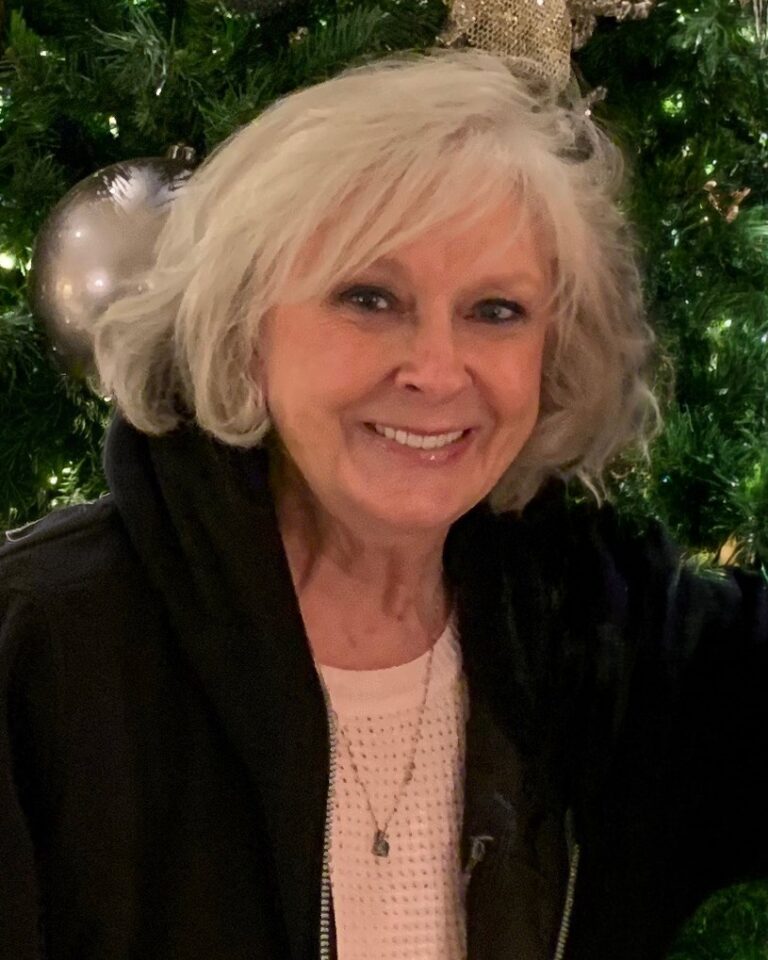 Diana Coleman smiling in front of a Christmas tree